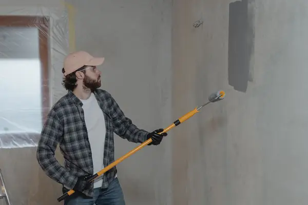 Painter rolling grey paint onto an interior wall in Knoxville